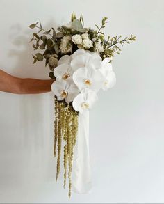 a bouquet of white flowers is held by a person's hand on a white background