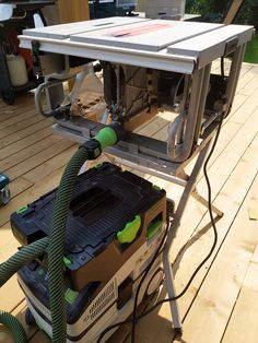 a table sawing on top of a wooden deck with a green hose attached to it