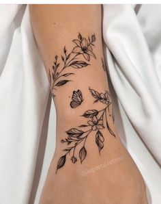 a woman's foot with flowers and leaves tattooed on the side of her leg