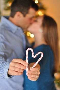 a man and woman kissing while holding candy canes