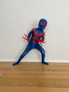 a blue and red spider - man statue sitting on top of a hard wood floor