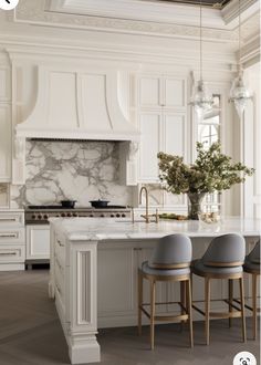 a kitchen with white cabinets and marble counter tops, two stools in front of the island