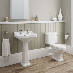 a white toilet sitting next to a sink and a bath tub in a bathroom with wood floors