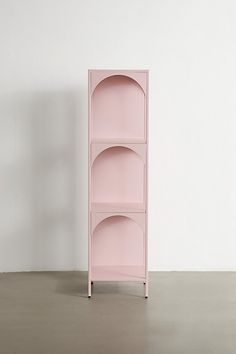 a pink shelf sitting on top of a floor next to a white wall