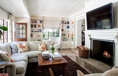 a living room filled with furniture and a flat screen tv mounted on the wall above a fire place