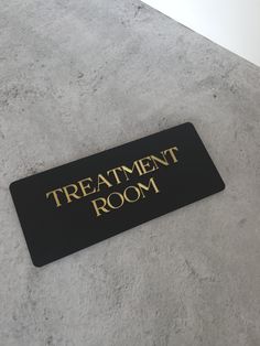 a black and gold sign that says treatment room on the floor in front of a white wall