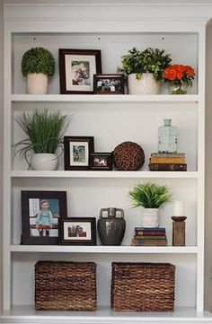 a white book shelf filled with pictures and plants