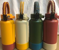 four different colored water bottles sitting next to each other on a table with a white curtain behind them