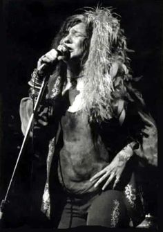 an old photo of a woman with long hair on stage holding a microphone in her hand