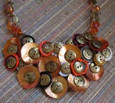 a necklace with many buttons attached to it on a carpeted surface and some beads hanging from the chain