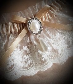 This vintage look garter is lovely in light ivory net lace over a champagne satin band. Decorated with a faux pearl and crystal finding. This garter is also available in plus size, just convo me with questions or your own design ideas! A blue satin rolled rose can be added to the inside of the band for your 'something blue'. Packaged in a view-top box tied with an elastic metallic bow, perfect for gift-giving or for safe-keeping after the wedding. Elegant Bridal Accessories With Lace Trim For Party, Elegant Bridal Accessories With Lace Trim, Fitted Cream Lace For Wedding Night, Adjustable Lace Bridal Accessories For Ceremony, Elegant Lace With Lace Trim For Ceremony, Cream Lace For Wedding Night, Elegant Bridal Accessories With Lace Trim For Wedding, Elegant Bridal Accessories With Delicate Lace For Party, Elegant Lace Bridal Accessories For Bridal Shower