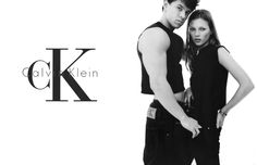 a man and woman standing next to each other in front of a white background with the letter k on it