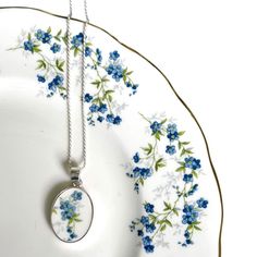 If you are seeking a romantic 9th (pottery), 18th (porcelain) or 20th anniversary (china) gift for your wife that she will always cherish, commemorate your love and this anniversary with this forget me not flower china necklace from eclectiQuas. This unique blue flower necklace features a dainty blue floral broken china pendant in an oval sterling silver setting and chain, and a repurposed china piece from a vintage forget me not china plate. In addition to being a beautiful fine bone china gift, this broken china jewelry piece highlights forget me not flowers that symbolize love, fidelity, and remembrance, promising that you will never forget the recipient, an occasion, a person in your thoughts. They also symbolize a connection that endures all challenges and measure of time. She will ch Repurposed China, Red Chinoiserie, 20th Anniversary Gifts, Piece Highlights, Elegant Gift Wrapping, Porcelain Necklace, Jewelry Sets Handmade, Forget Me Not Flower, Broken China Jewelry