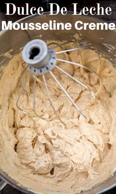 a large metal bowl filled with batter on top of a counter next to a whisk