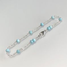 Natural Caribbean aqua blue larimar bracelet, wire-wrapped in sterling silver. This minimal and feminine bracelet features genuine, high-quality larimar gemstones meticulously wire-wrapped onto half-inch segments of strong, double-link sterling silver chain. These pastel blue stones are micro-faceted and pair beautifully with the silver for a delicate look.  A lobster claw clasp, adorned with double gemstone, finishes this bracelet. Dainty and subtle, this lovely bracelet is perfect by itself or layered with others. Details: *  length: please choose at check out genuine, faceted AAA Caribbean blue larimar (4 mm) double-link sterling silver chain, clasp and components *  Choosing your length at checkout:  I recommend 1/2 inch larger than your actual wrist/ankle size. Bracelet/anklet is meas Feminine Bracelet, Bracelet Business, Larimar Bracelet, Blue Beaded Bracelets, Caribbean Blue, Blue Stones, Bracelet Dainty, Pastel Blue, Sterling Silver Chain