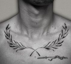 a man's chest with an arrow and laurel wreath tattoo on the upper part of his chest