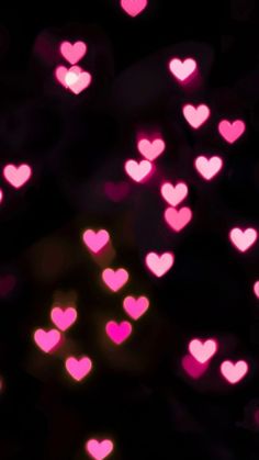 many pink hearts are arranged in the shape of heart shapes on a black background with blurry lights