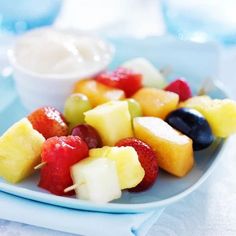 fruit skewers on a blue plate with dip