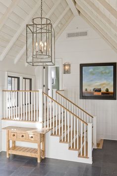 a white house with wooden stairs and a painting hanging on the wall above it's railings