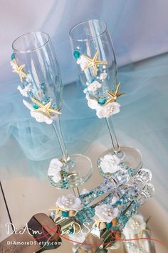 two wine glasses with starfish and pearls on them are sitting next to each other