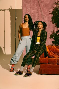 two women standing next to each other in front of a couch