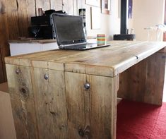 a laptop computer sitting on top of a wooden desk next to a red carpeted floor