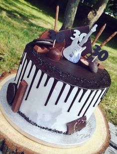 a birthday cake with chocolate icing and decorations on the top is sitting on a tree stump