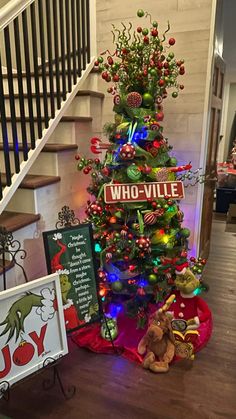 a christmas tree decorated with lights and decorations in front of a staircase case that reads whovillee