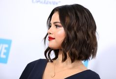 a close up of a person wearing a black dress with red lipstick on her lips