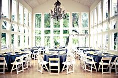 a room filled with lots of tables covered in black and white cloths next to large windows