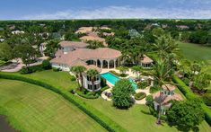 an aerial view of a large home surrounded by palm trees and lush green lawns