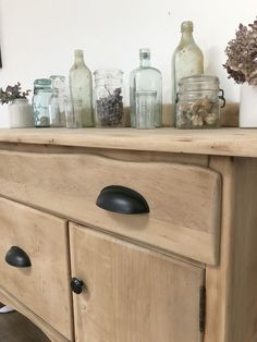 an old dresser with jars and flowers on top