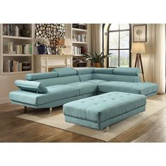 a blue sectional couch sitting on top of a wooden floor next to a book shelf