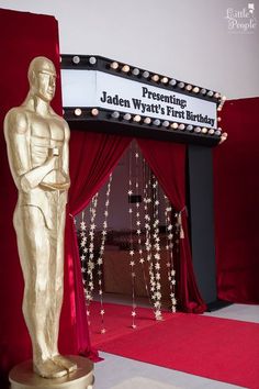 an oscar statue in front of a red curtain