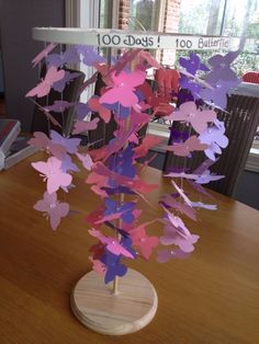 a wooden table topped with a vase filled with paper cut butterflies on top of it