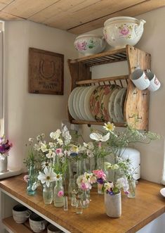 a wooden table topped with lots of vases filled with white and pink flowers on top of it