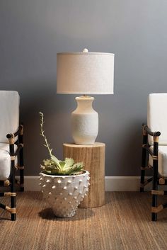 two chairs and a table with a lamp on it in front of a blue wall