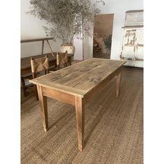 a wooden table sitting on top of a rug next to two chairs and a plant