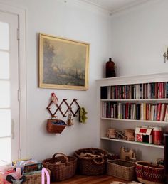 the bookshelves are full of books and baskets on the floor in this room