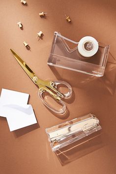 a pair of scissors sitting next to a tape dispenser on top of a table