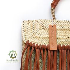 a woven bag with leather handles and tassels hanging from it's side