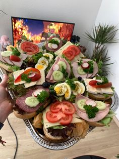 a platter filled with lots of different types of sandwiches on top of each other