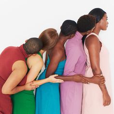 four women in different colored dresses hugging each other