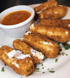 some fried food on a white plate next to a small bowl of sauce and dipping sauce