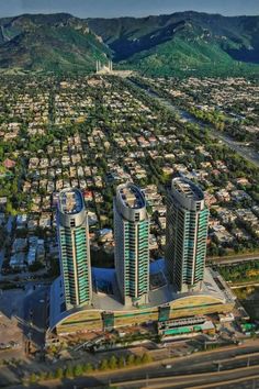 an aerial view of a city with mountains in the back ground and buildings on both sides