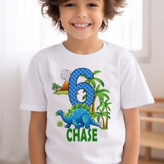 a young boy wearing a white shirt with the number six on it and an image of a dinosaur