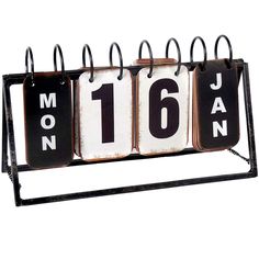 a metal calendar with the number sixteen on it's front and back sides, hanging from an iron frame