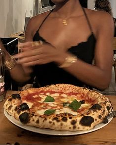 a woman sitting at a table in front of a pizza