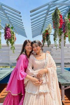 two women standing next to each other in front of a table with flowers on it