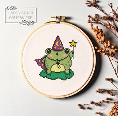 a cross stitch frog with a hat on it's head